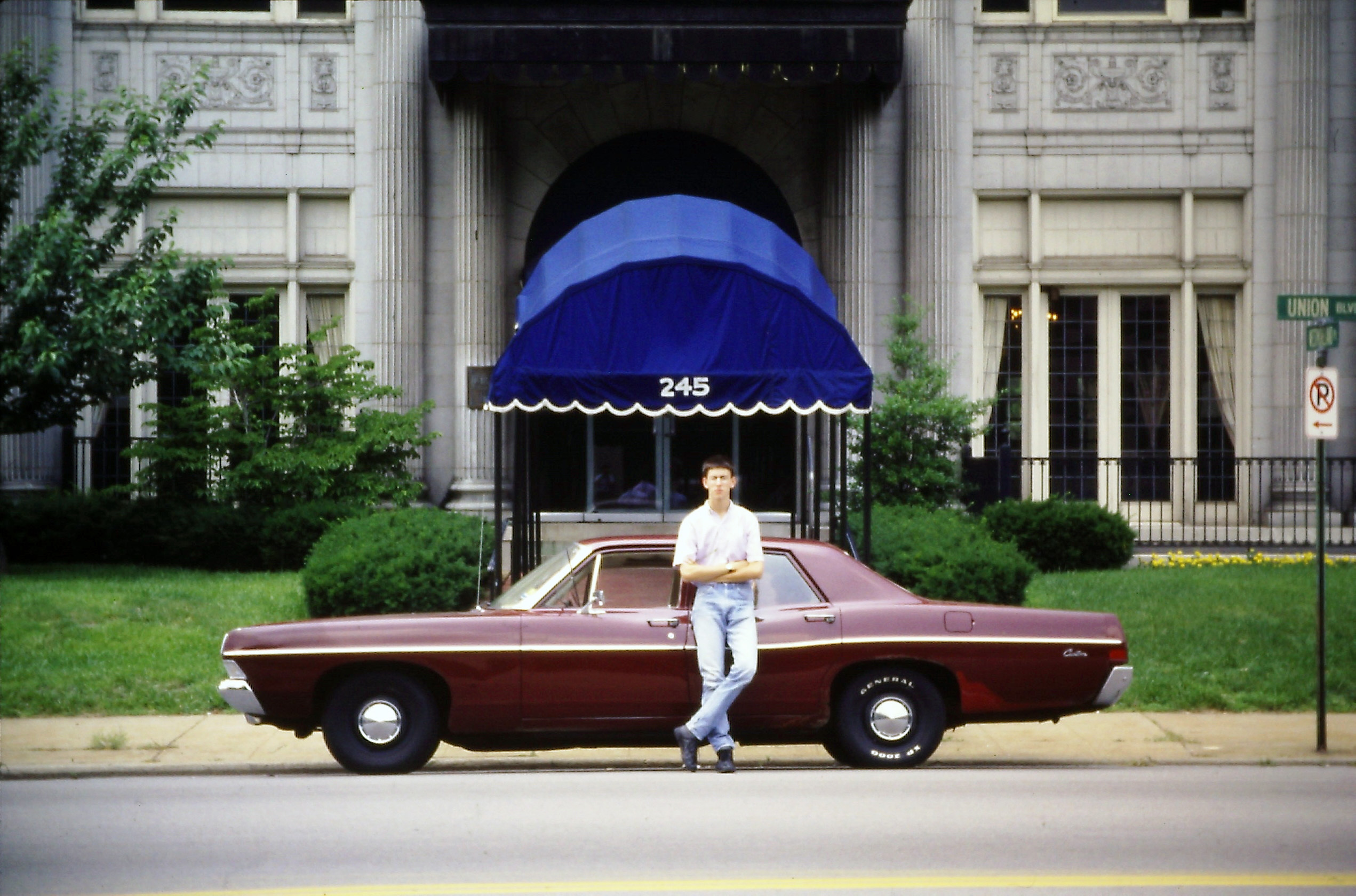 The author as a youth standing next to a 1968 maroon Ford Galaxie