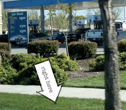 A gas station, overlaid with an arrow pointing at the grass saying ‘right here’