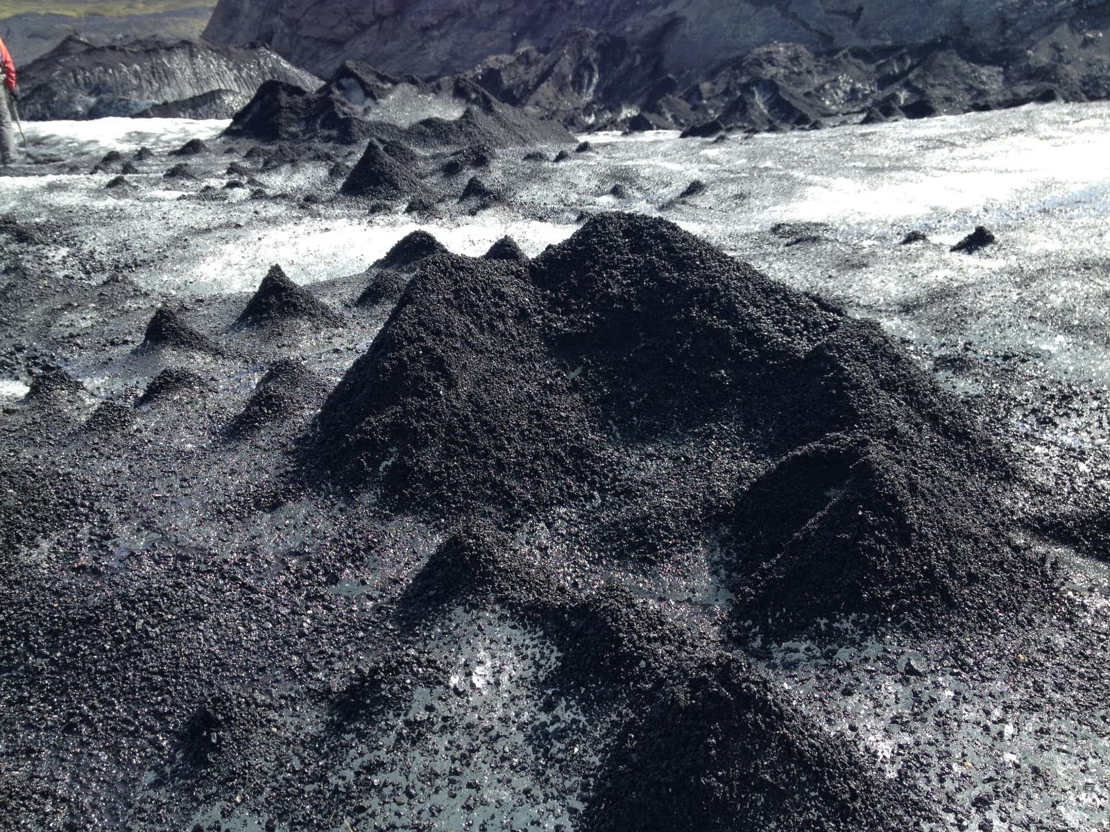 A glacier largely covered with ash, much of it stacked in little cone shapes