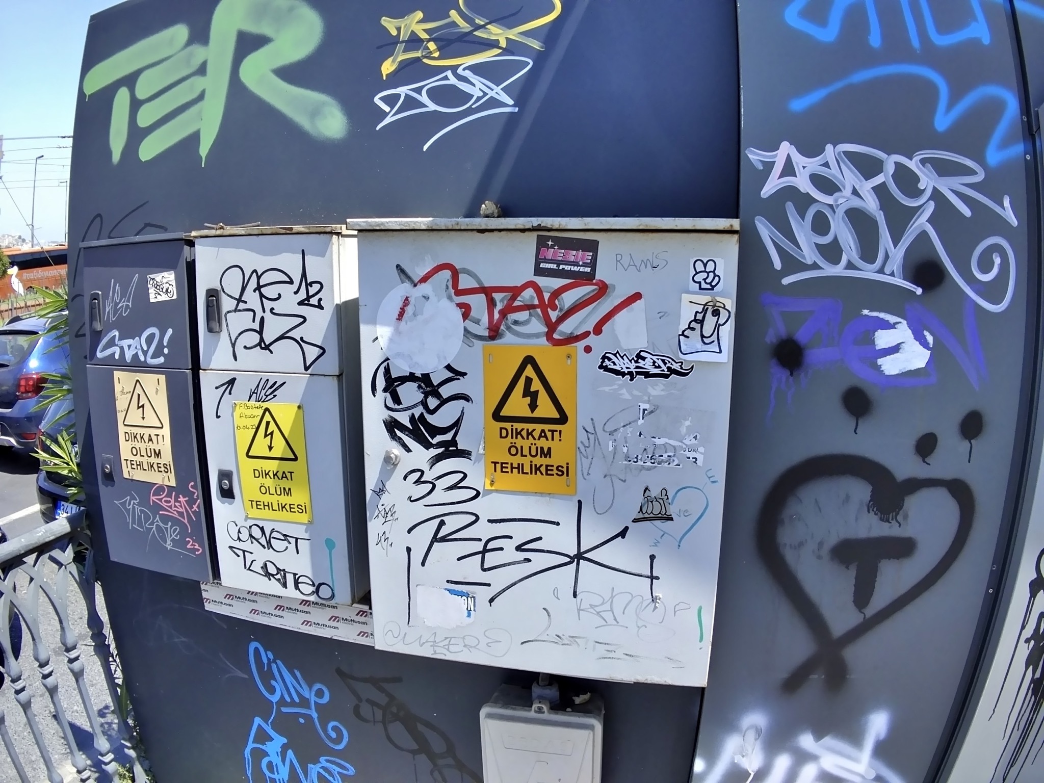 A power transformer box on the street with stickers and graffiti