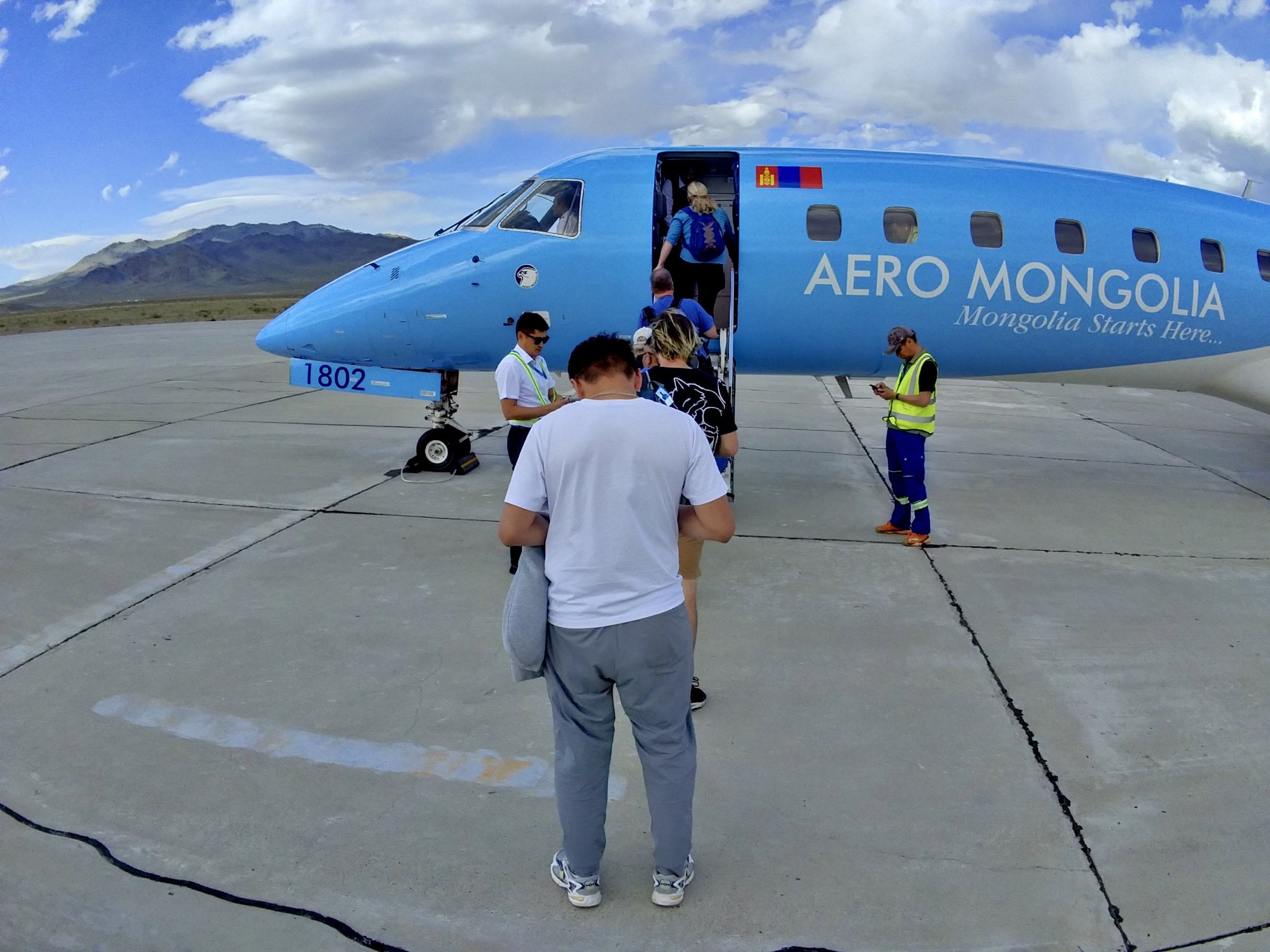 A small, light blue Aero Mongolia plane on the runway